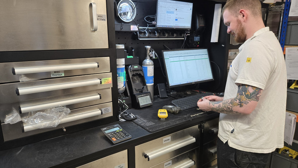 Technician adjusting a total station on the workshop bench, with rotating lasers and test equipment alongside